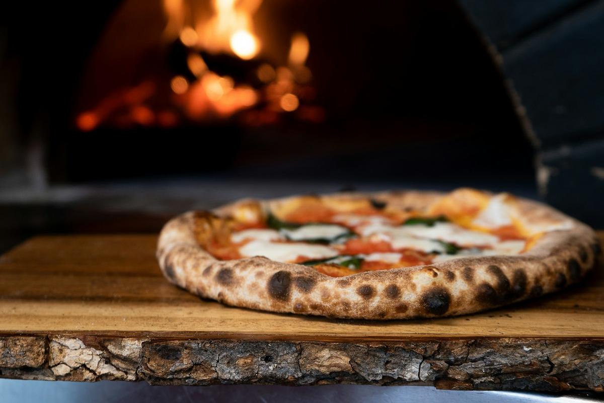 Pizza davanti al forno a legna acceso